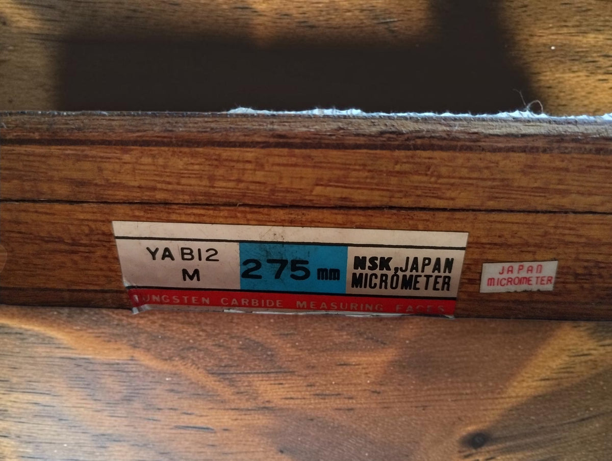 Label on the wooden case marked YABI2 M, 275 mm, NSK Japan Micrometer and tungsten carbide measuring faces.

