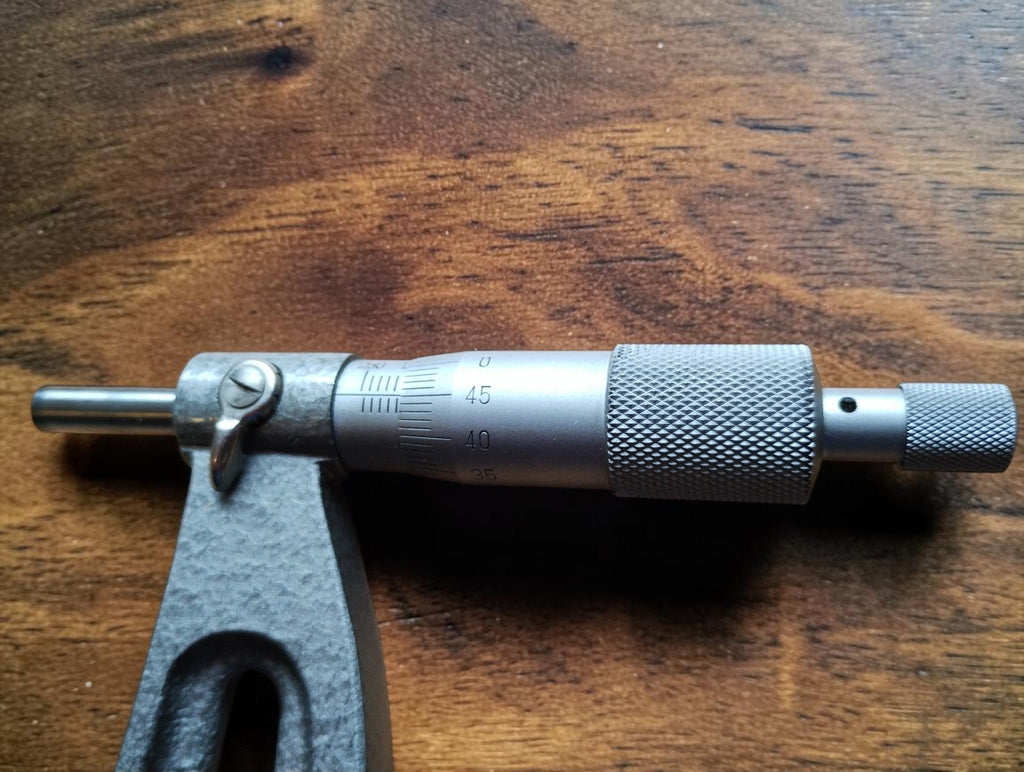 Close-up of the NSK micrometer head showing the graduated thimble, knurled adjustment surfaces, locking lever and spindle.
