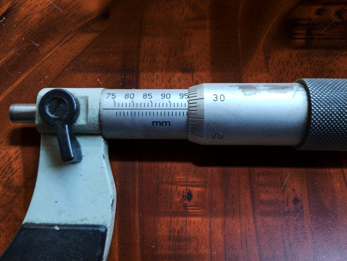 Close-up of the outside micrometer's millimeter scale, graduated thimble and locking lever.
