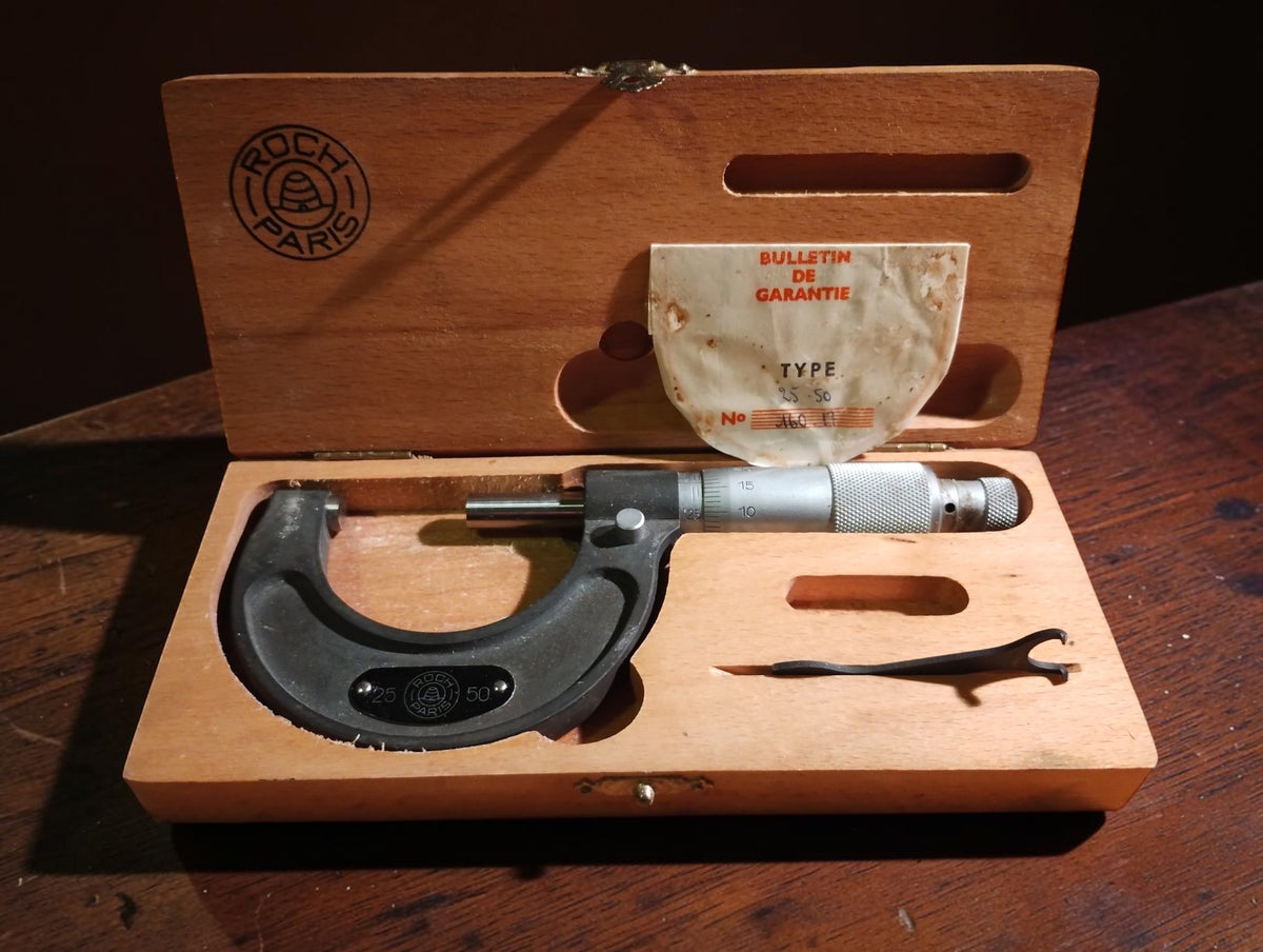 Roch Paris 25–50 mm outside micrometer in its original wooden case with adjustment wrench and French guarantee document.
