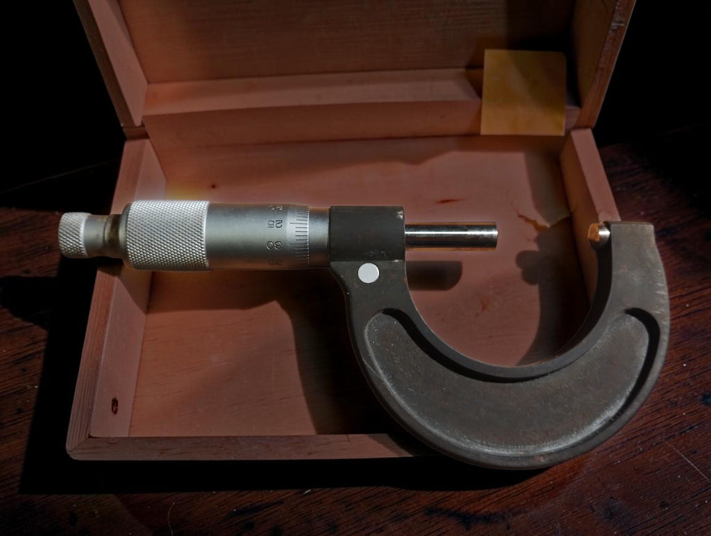 Rear view of the Roch Paris 25–50 mm outside micrometer resting across its open wooden case.
