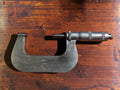 Carl Zeiss Jena 50–75 mm outside micrometer on a wooden surface, showing the metal frame and measuring spindle.
