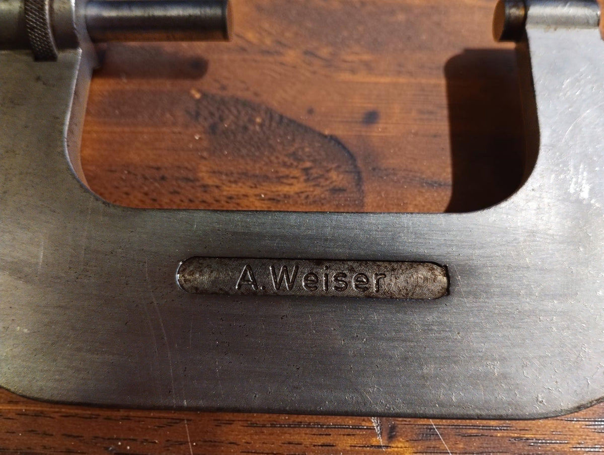 Close-up of the A. Weiser nameplate on the metal micrometer frame, showing surface wear and scratches.
