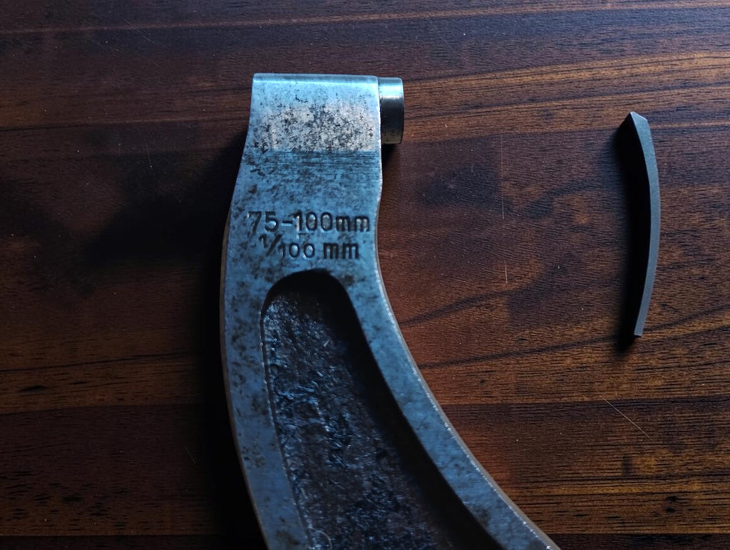 Close-up of the micrometer frame marked 75–100 mm and 1/100 mm, showing surface wear.
