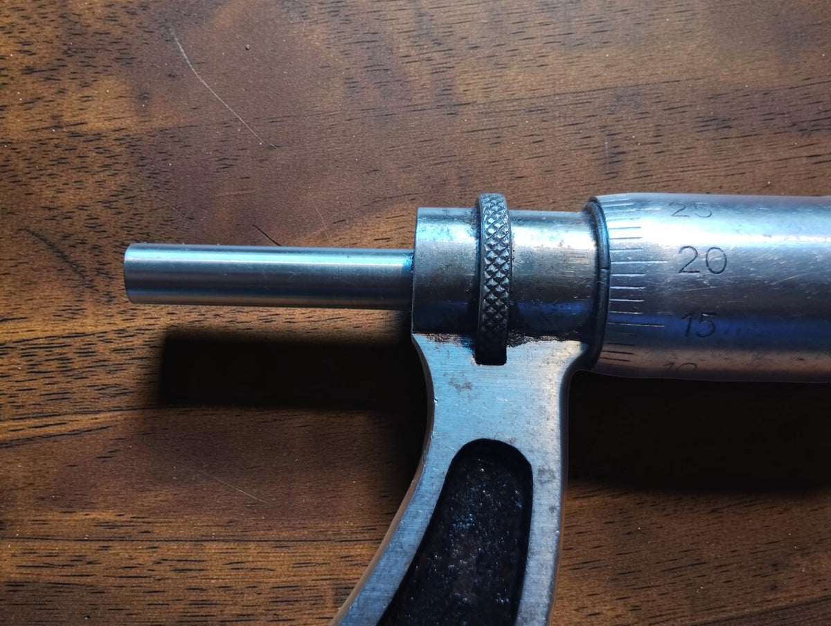 Close-up of the outside micrometer's measuring spindle, knurled locking ring and numbered thimble scale.
