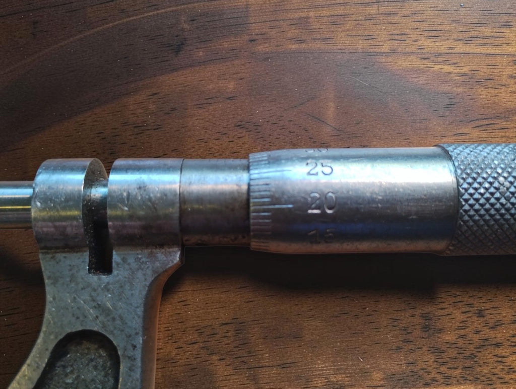 Close-up of the outside micrometer's graduated thimble, sleeve and spindle lock, showing surface wear.
