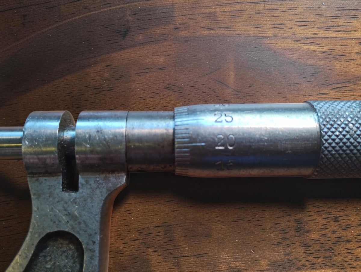 Close-up of the outside micrometer's graduated thimble, sleeve and spindle lock, showing surface wear.
