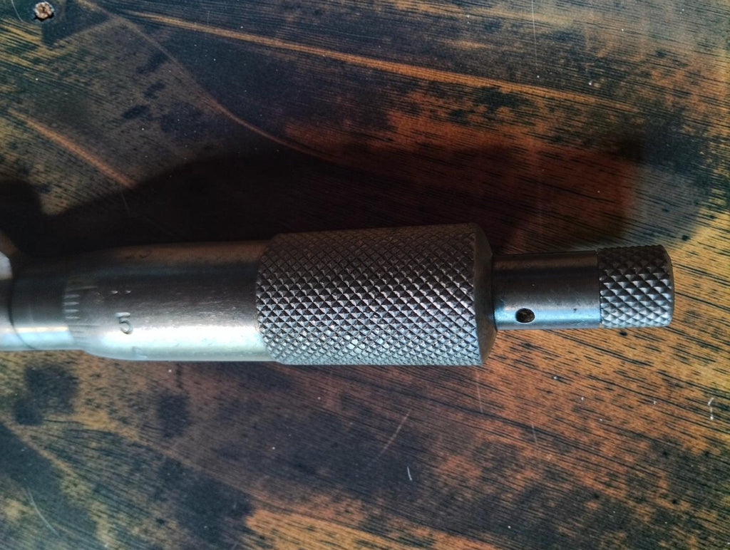 Detail of the knurled adjustment thimble and smaller end knob of a vintage disc micrometer.
