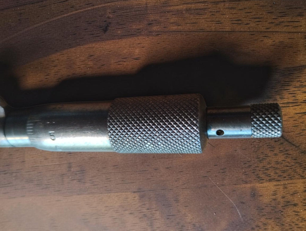Close-up of the outside micrometer's knurled adjustment thimble and smaller end knob.
