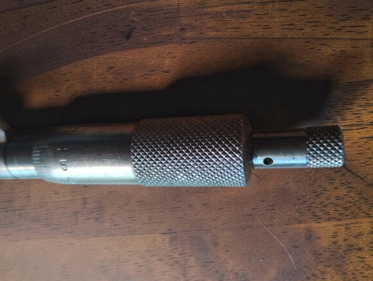 Close-up of the outside micrometer's knurled adjustment thimble and smaller end knob.

