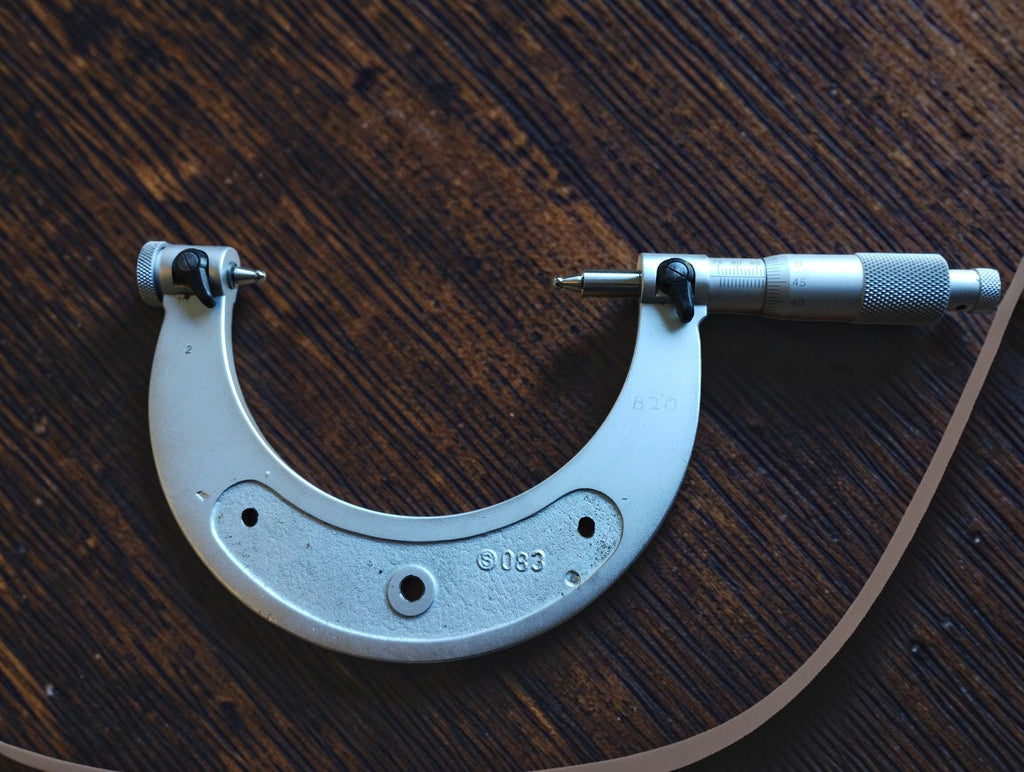Front view of a vintage 75–100 mm outside micrometer with rounded measuring tips and the adjustment thimble on the right.
