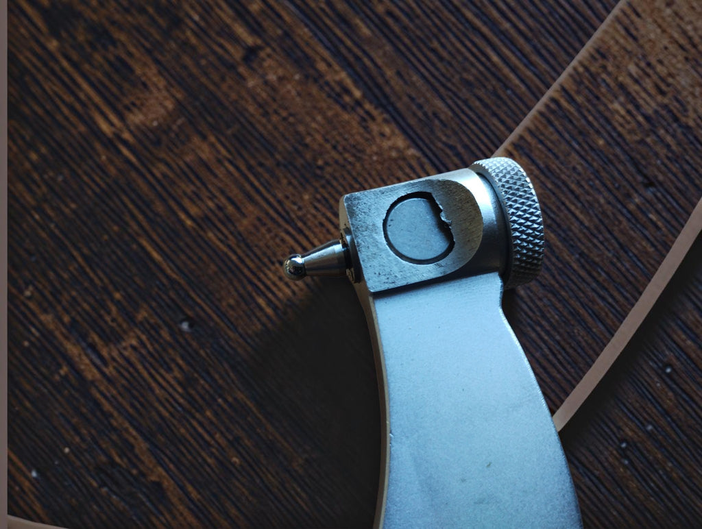 Reverse close-up of the micrometer anvil assembly showing the rounded measuring tip and knurled adjustment knob.
