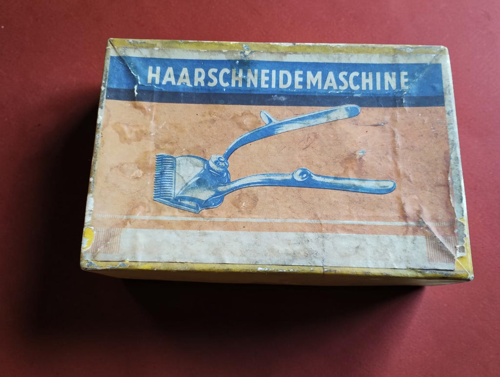 Vintage cardboard box with German Haarschneidemaschine lettering and an illustration of a manual hair clipper
