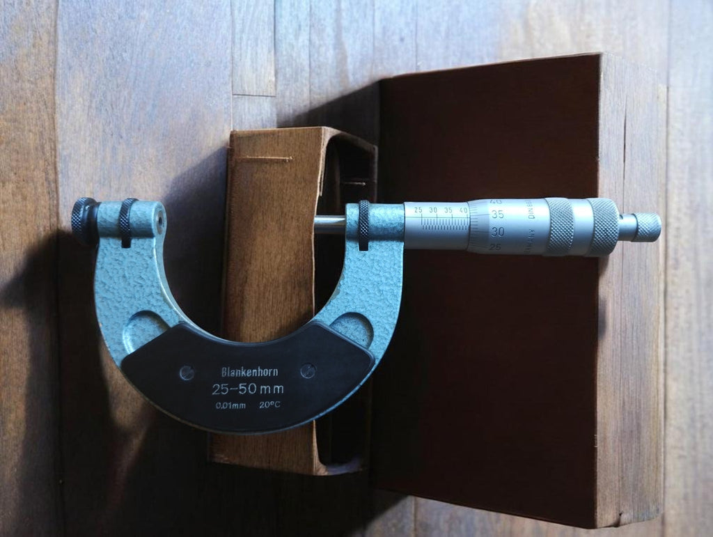 Blankenhorn 25–50 mm thread micrometer standing upright in front of its open wooden storage case.
