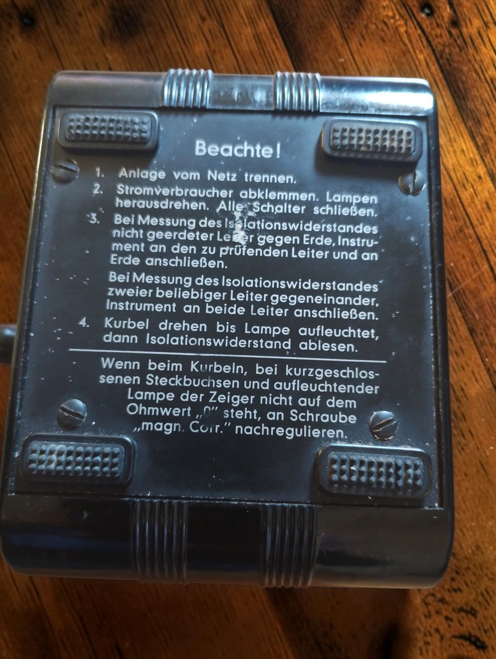 Rear of the Gossen ISOGNOM insulation tester showing German operating instructions, four feet and mounting screws.
