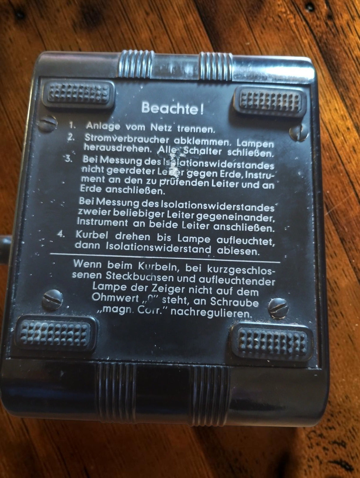 Rear of the Gossen ISOGNOM insulation tester showing German operating instructions, four feet and mounting screws.
