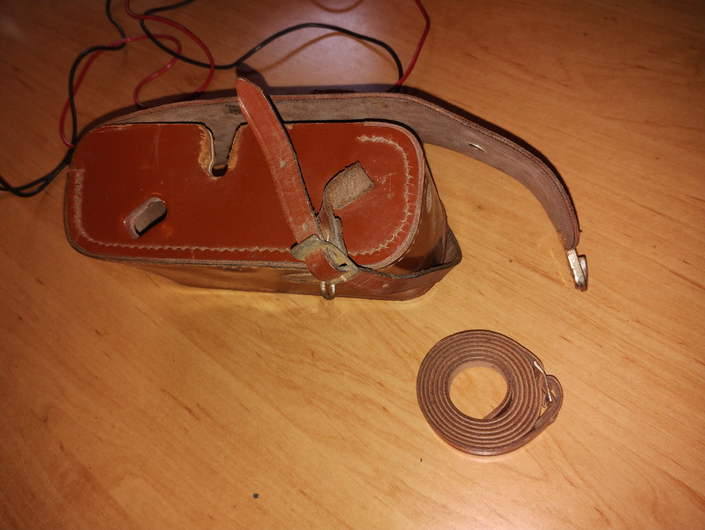 Brown leather carrying case for the Gossen ISOGNOM tester, with visible wear and a separate rolled leather strap.
