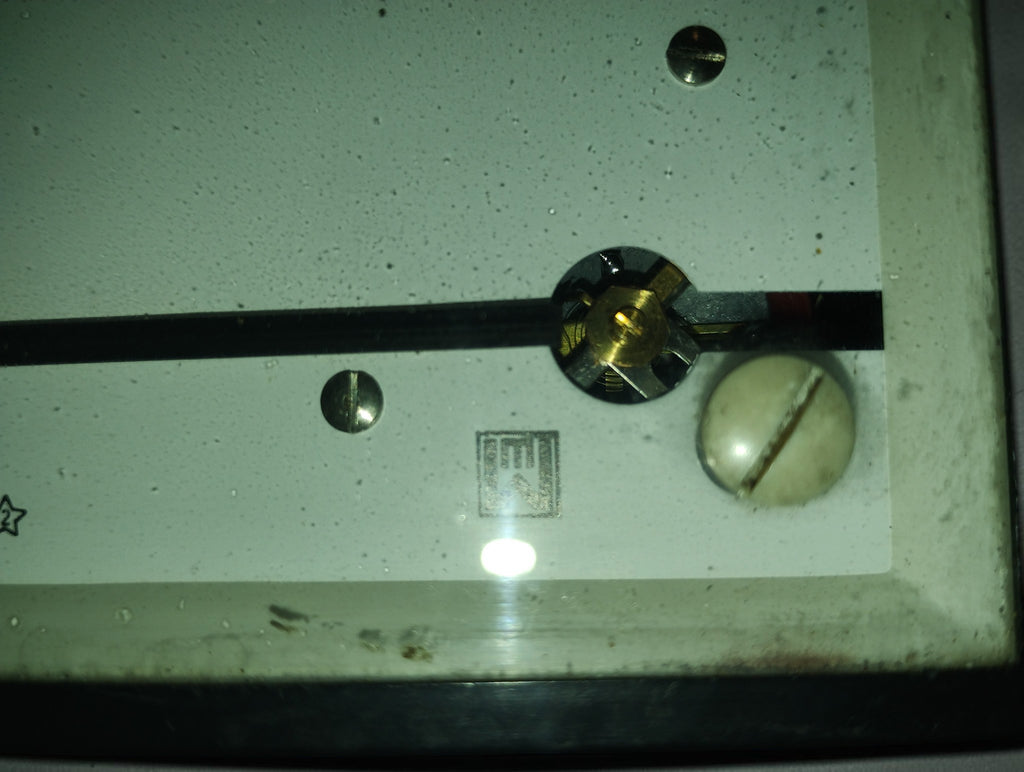 Close-up of the EAW maker's logo, pointer mechanism and adjustment screw on a vintage AC ammeter
