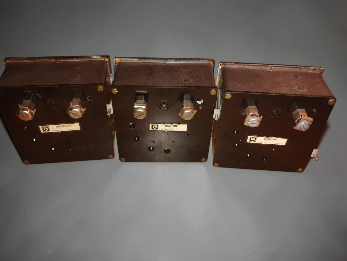 Rear view of three vintage EAW Berlin-Treptow AC ammeters showing connection terminals and historical inspection labels
