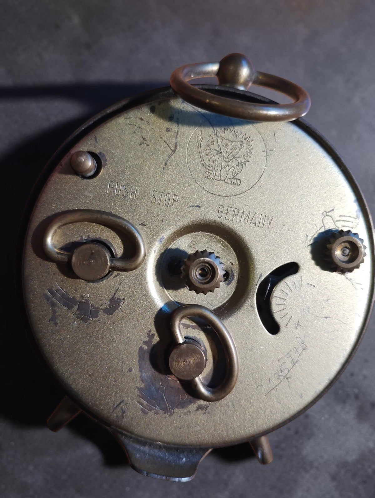 Back of the Jerger mechanical alarm clock with the lion emblem, Push Stop and Germany markings, winding keys and visible wear.
