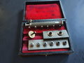 Antique pocket watch mainspring winder with interchangeable parts in a red-lined wooden case

