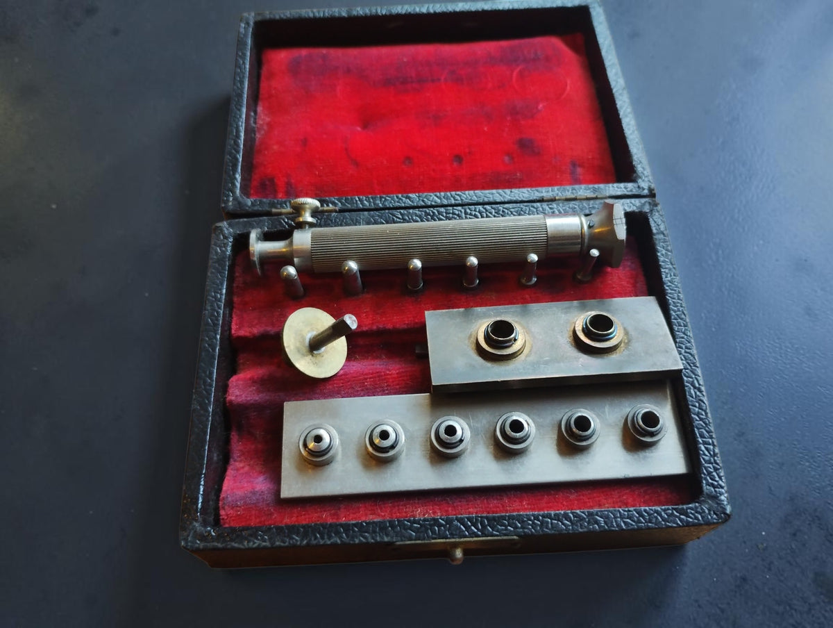 Antique pocket watch mainspring winder with interchangeable parts in a red-lined wooden case
