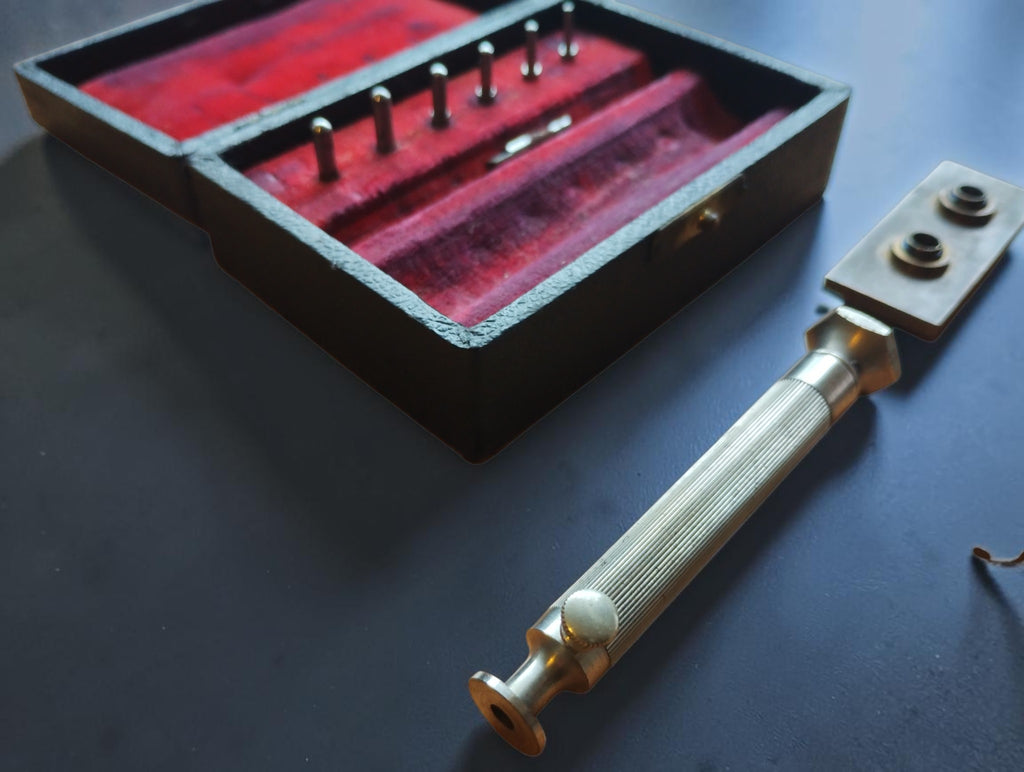 Close-up of the mainspring winder's ribbed metal handle beside the red-lined case
