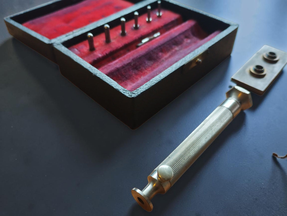 Close-up of the mainspring winder's ribbed metal handle beside the red-lined case
