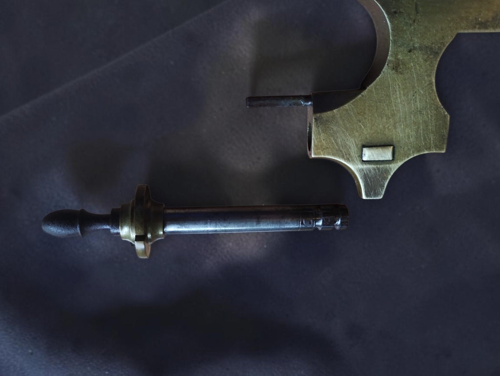 Detail of a detached steel runner and wooden handle below the brass Jacot tool frame
