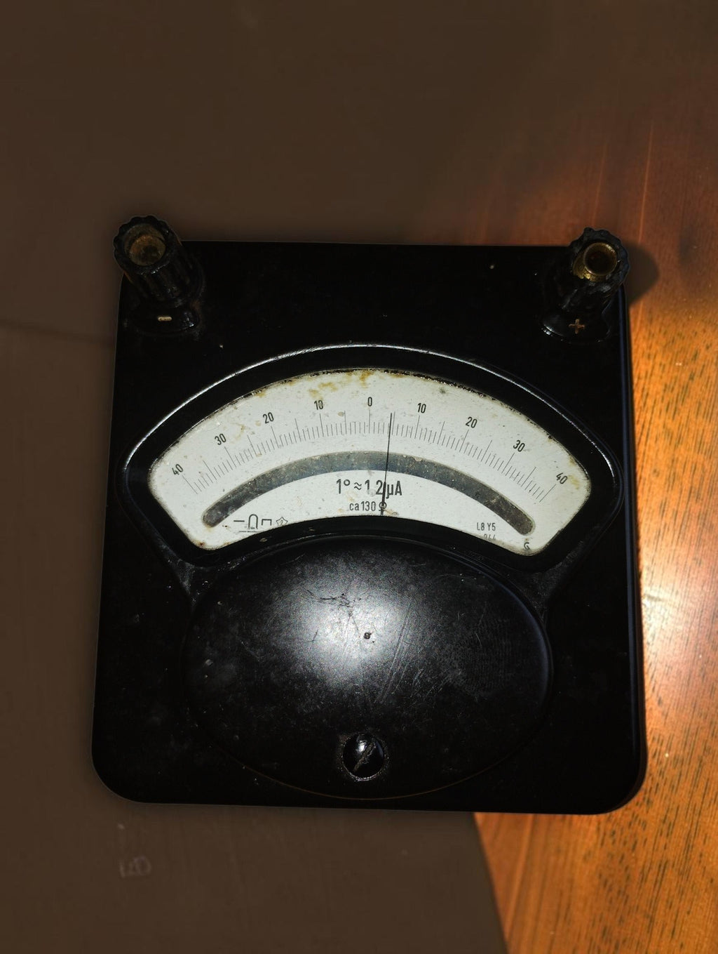 Vintage analog galvanometer in a black Bakelite case, with a center-zero scale and two connection terminals.

