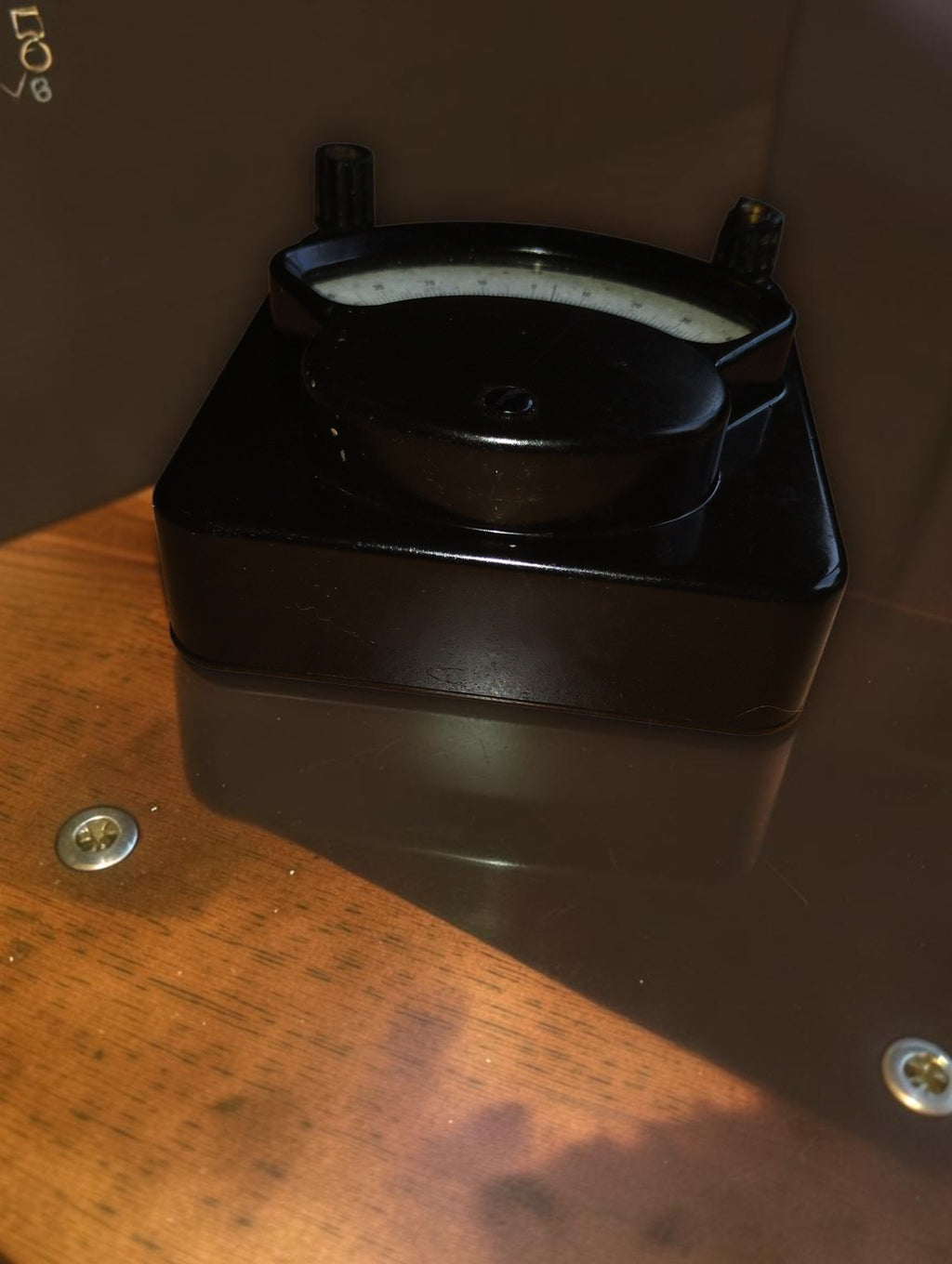 Side view of the vintage galvanometer showing the depth and sloping profile of its black Bakelite housing.
