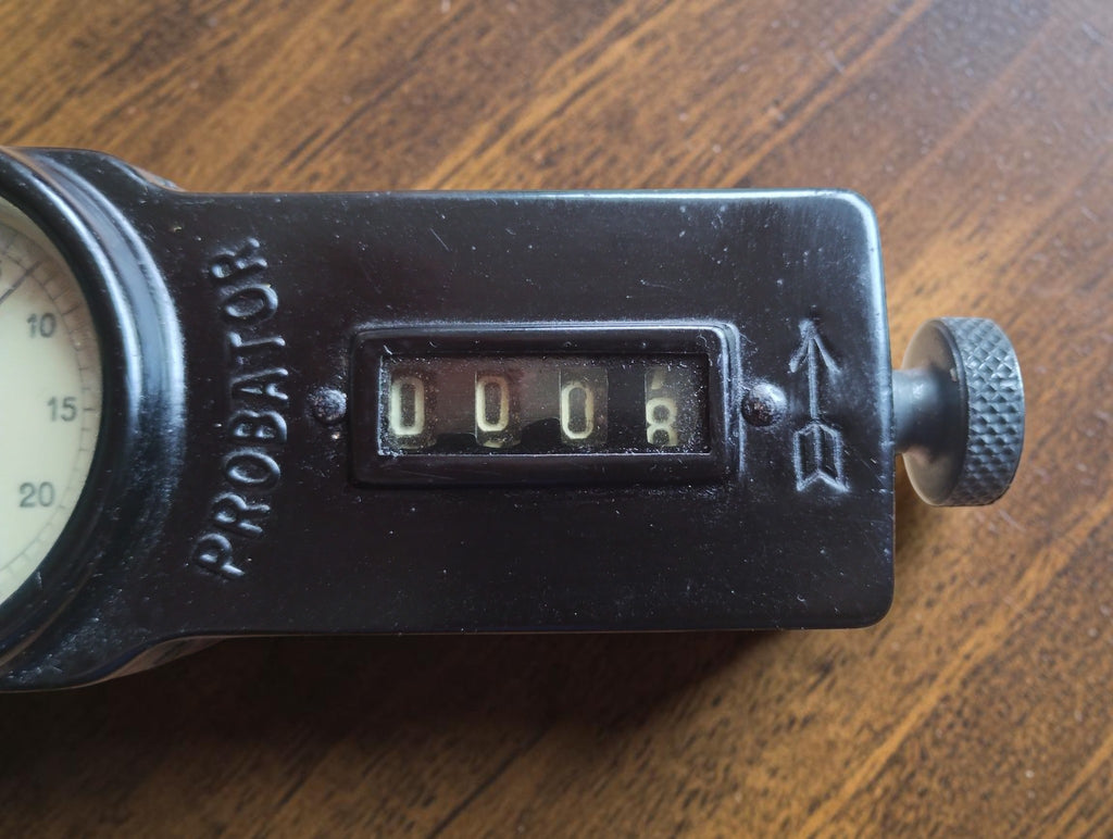 Mechanical counter window, embossed Probator name and knurled control knob on the black tachometer housing
