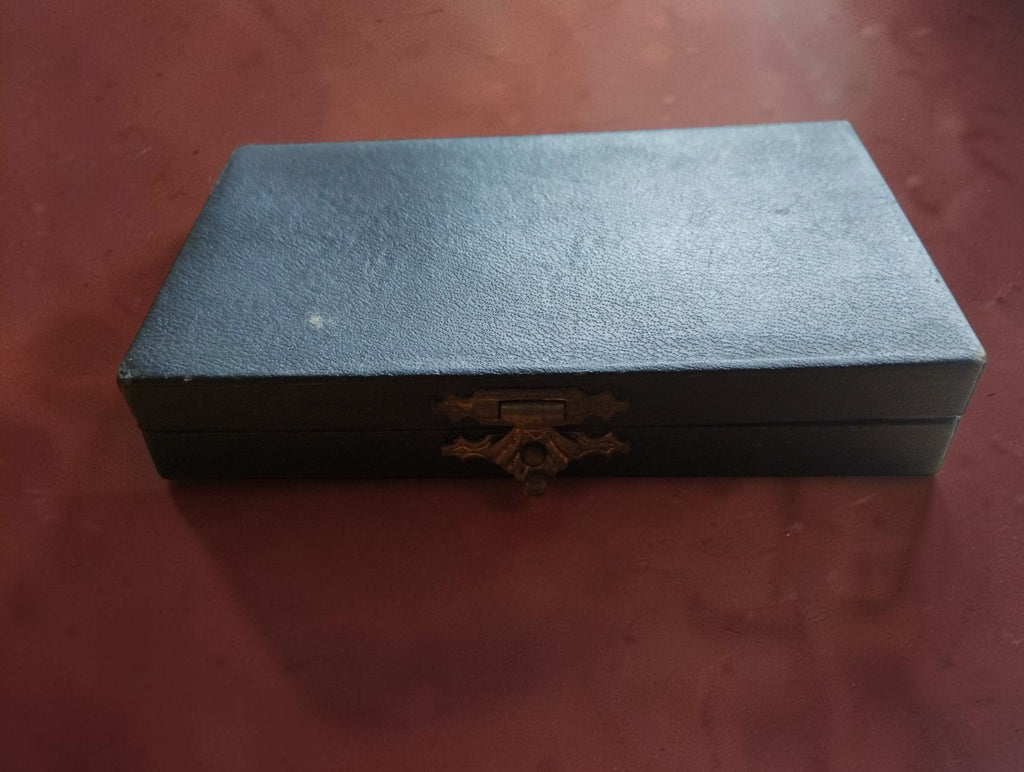 Closed vintage storage box for a complete set of metal clock dial numerals.
