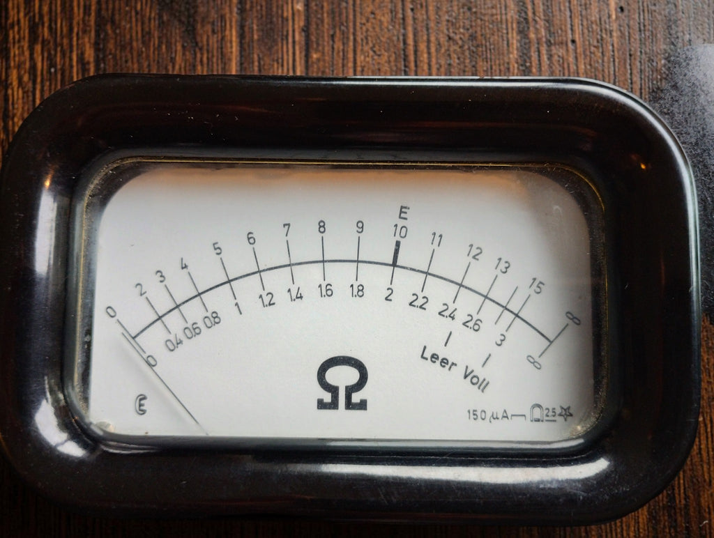 Close-up of the RESITEST analog resistance scale with ohm symbol and battery level markings
