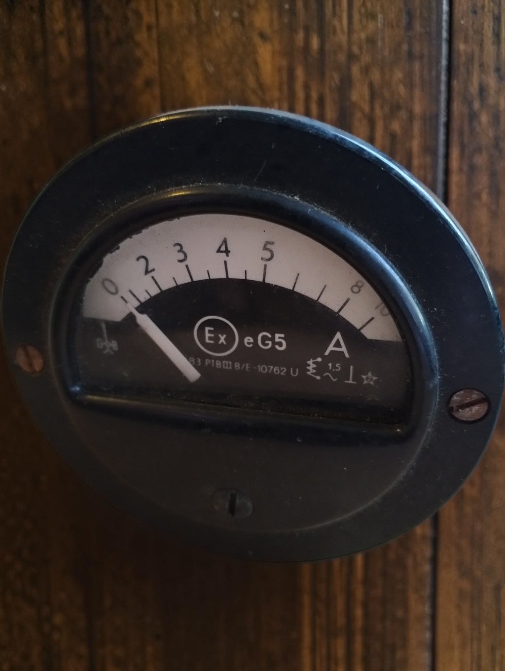Vintage round ammeter with Ex e G5 marking, a black dial and a white pointer in a black housing.
