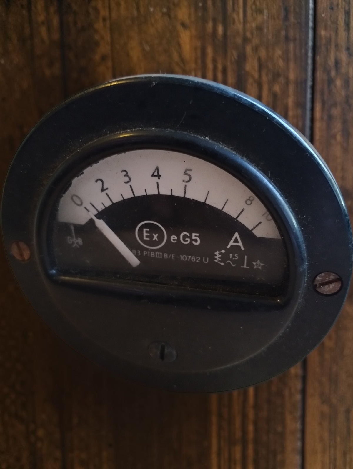Vintage round ammeter with Ex e G5 marking, a black dial and a white pointer in a black housing.
