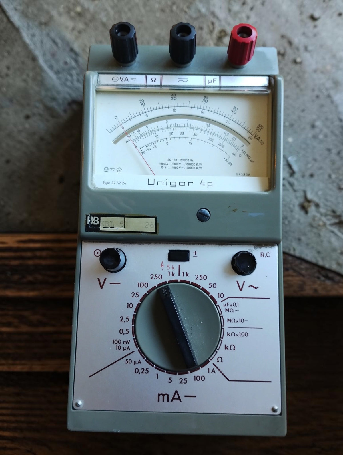 Unigor 4p analog multimeter showing the measurement scales, range selector and three connection terminals
