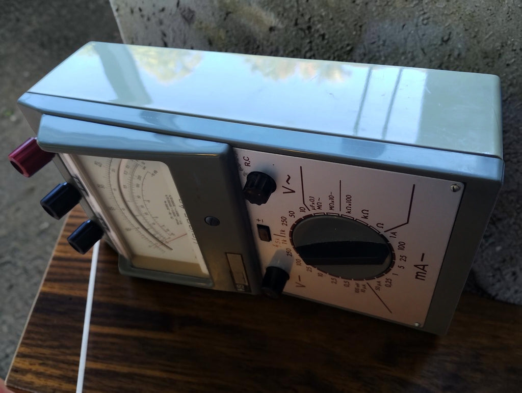 Side view of the Unigor 4p analog multimeter showing the metal housing and angled front panel
