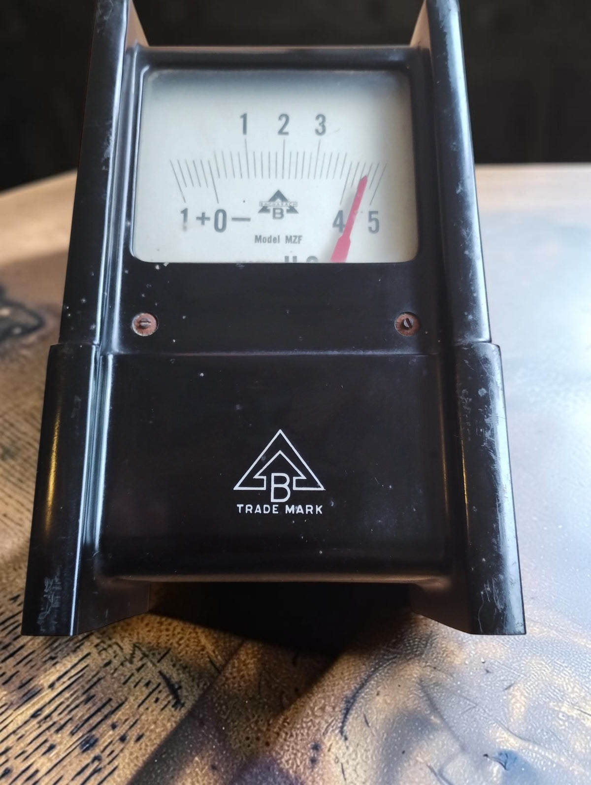 Front view of the vintage Bacharach Model MZF pressure gauge with a black housing, white dial, red pointer and triangular B trademark.

