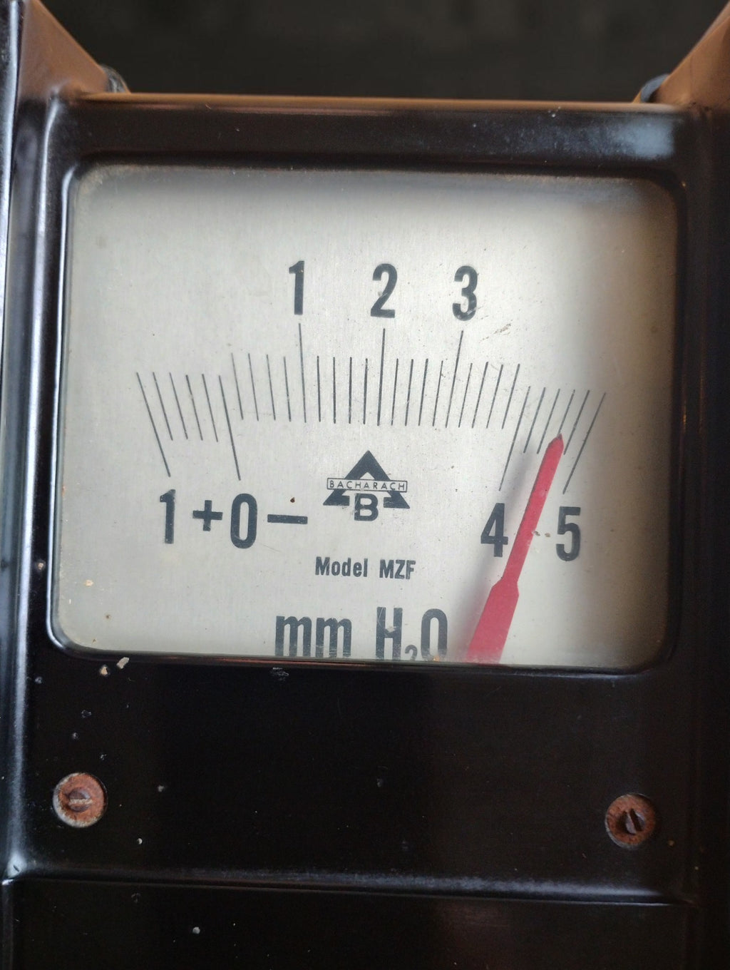 Close-up of the Bacharach Model MZF dial showing the mm H₂O scale, red pointer and triangular B trademark.
