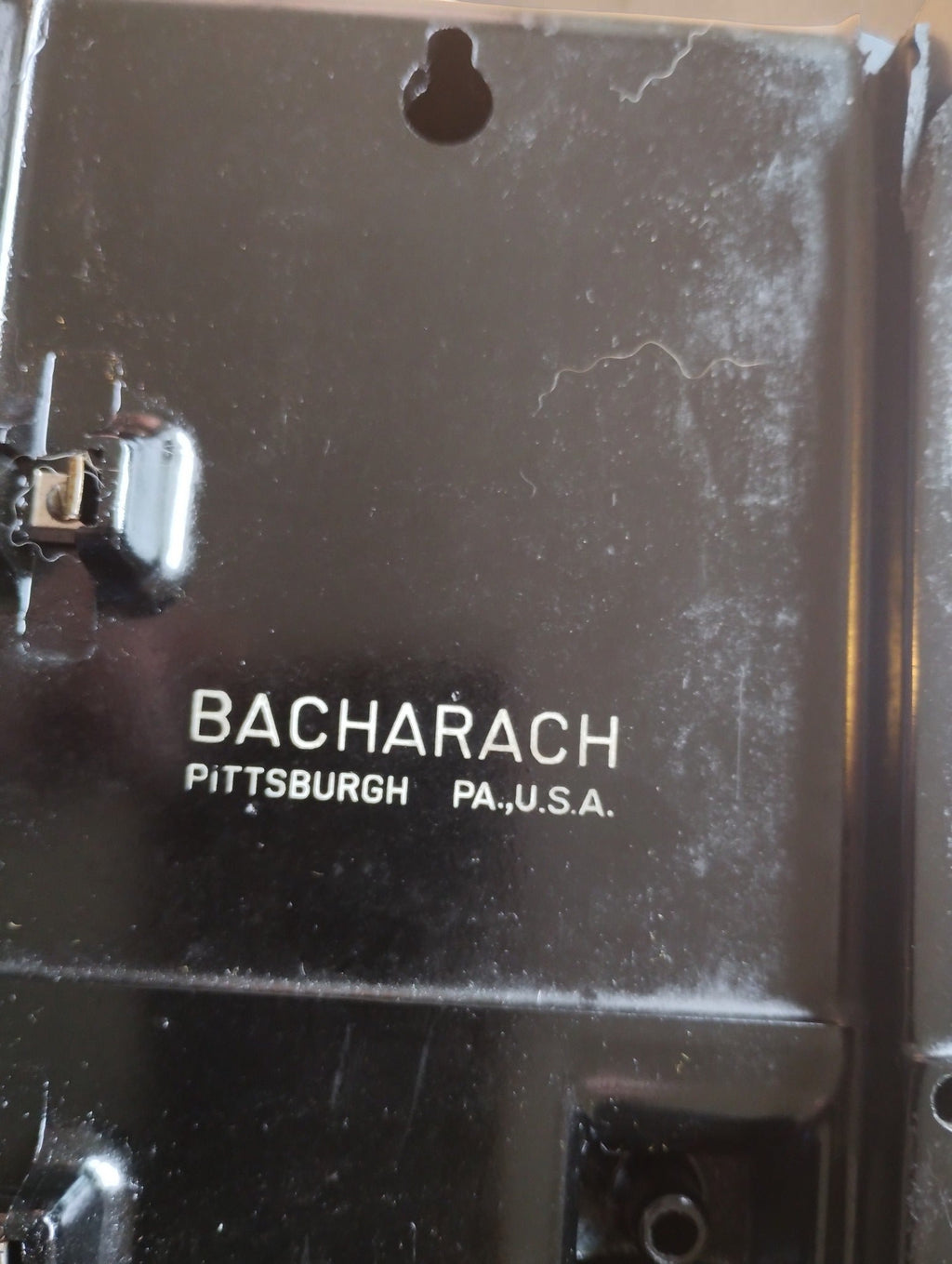 Close-up of the Bacharach Pittsburgh PA U.S.A. marking on the rear housing, showing surface scratches and paint wear.
