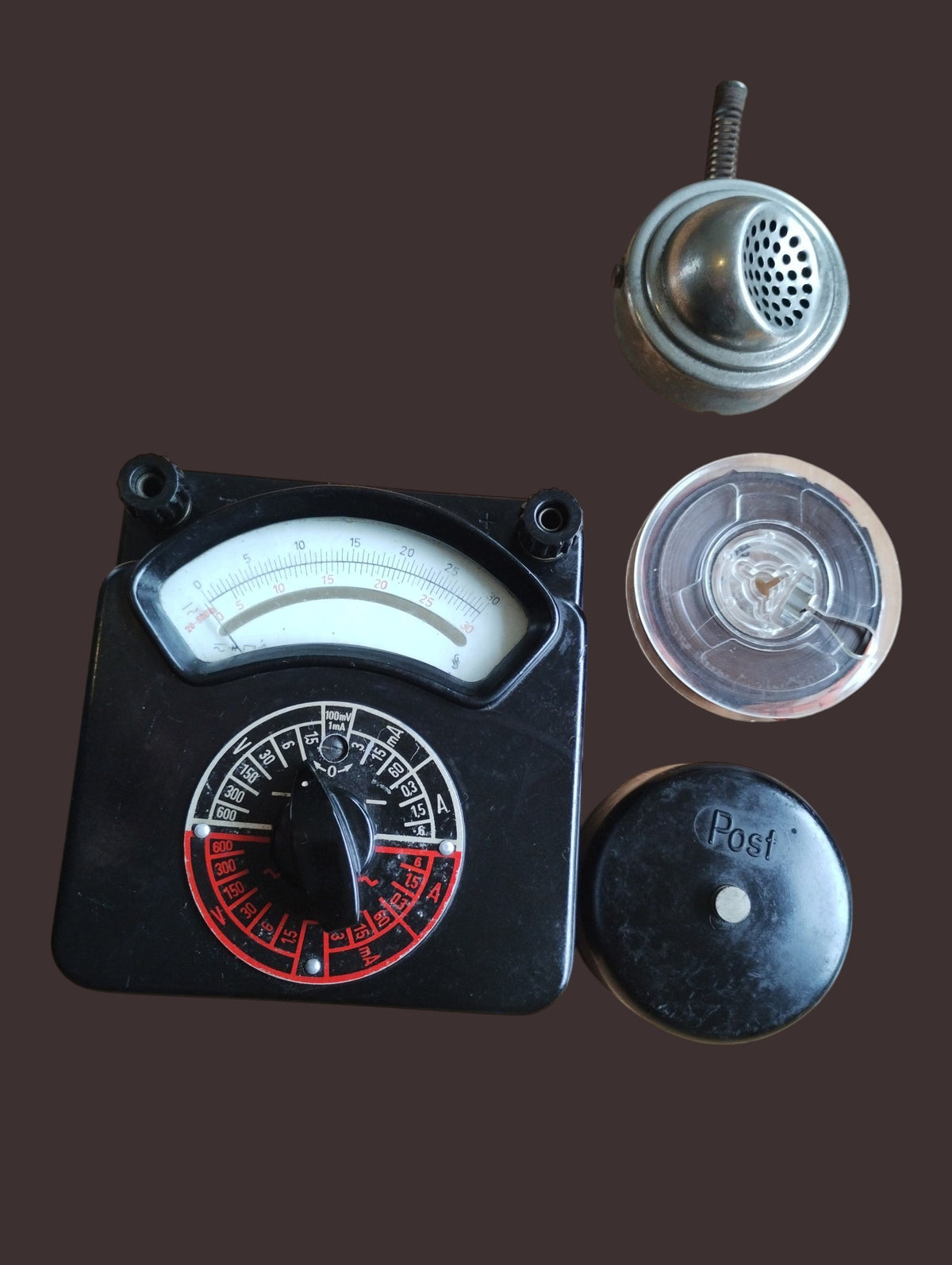 Siemens & Halske Post Multizet 1 analog meter beside a metal telephone capsule, cable spool, and black Post-marked cap.
