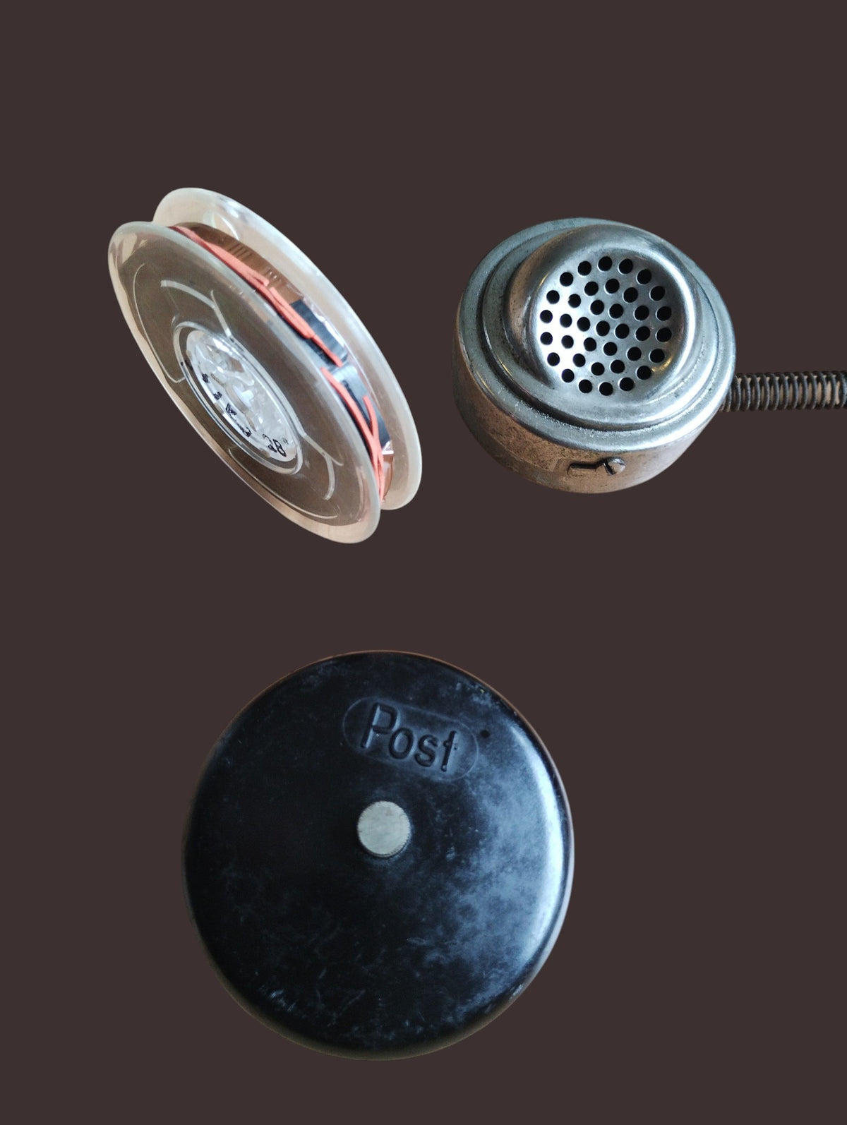 Telephone test accessories from the Post set: metal capsule, cable spool, and black cap marked Post.
