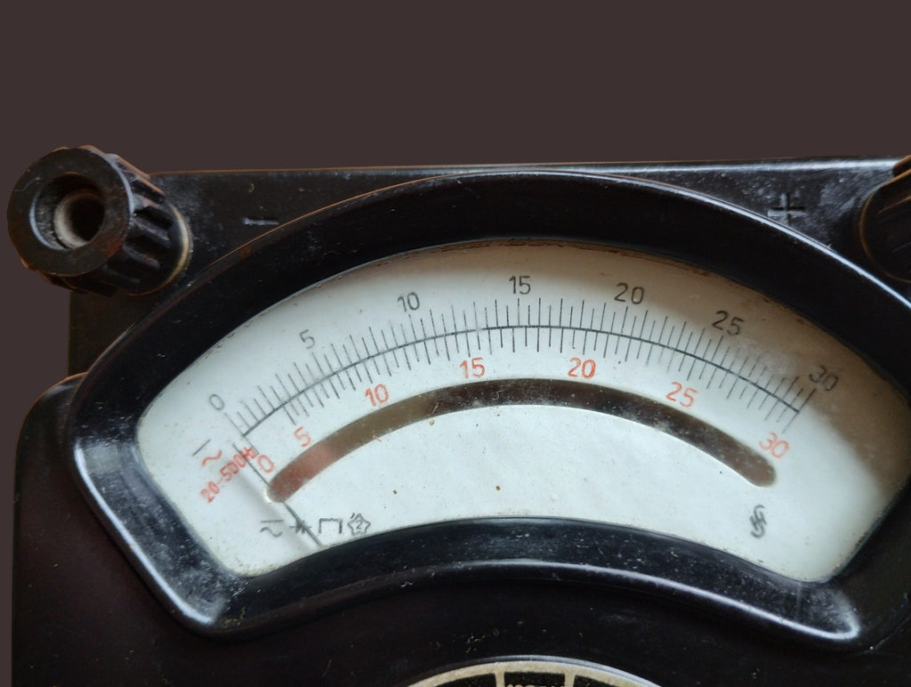 Close-up of the Multizet 1 meter scale with black and red graduations, needle, and visible age-related wear.
