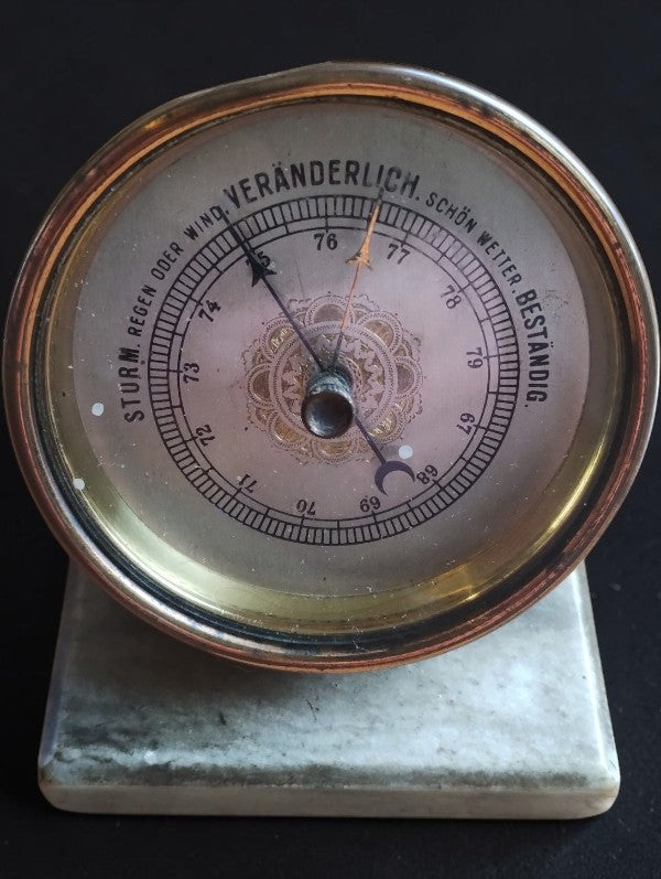 Antique German aneroid desk barometer with brass case, decorative dial, and marble base, front view.

