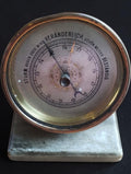 Antique German aneroid desk barometer with brass case, decorative dial, and marble base, front view.
