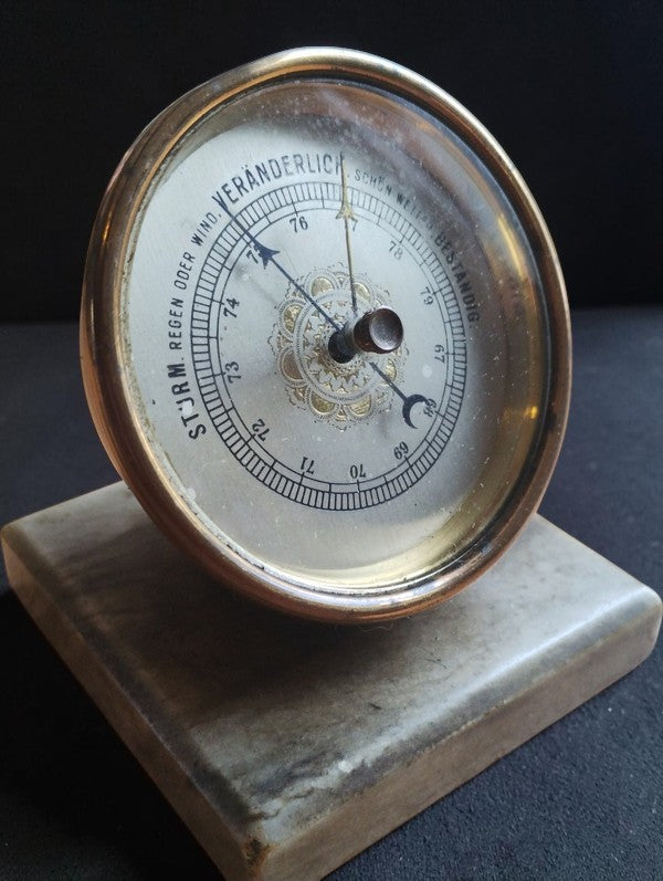 Angled front view of the unbranded brass desk barometer with German weather markings and marble base.
