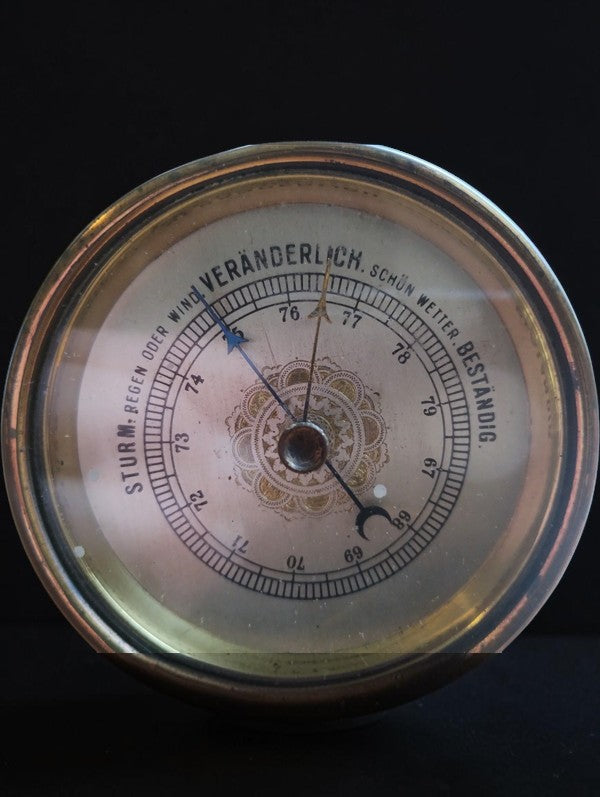 Close-up of the barometer dial with German weather markings, decorative gold-tone rosette, and pointers.
