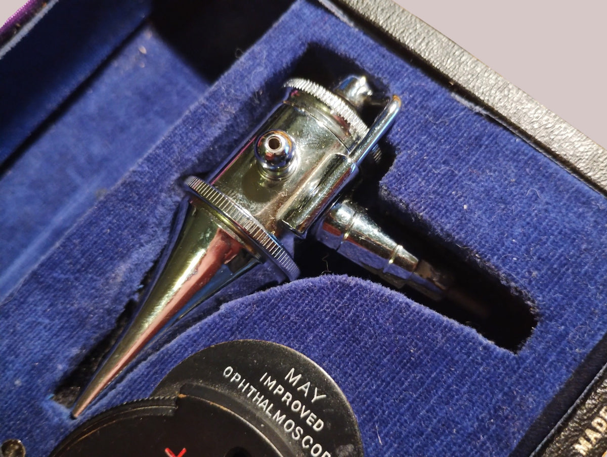 Metal instrument head beside the May Improved Ophthalmoscope in the blue-lined Gowllands case
