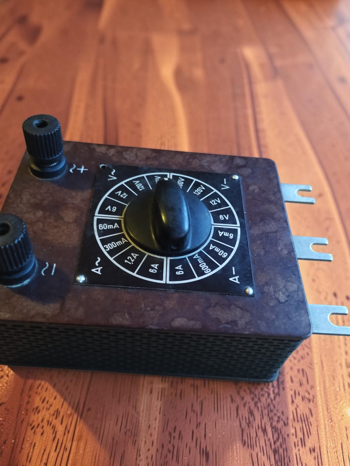 Vintage Bakelite range selector viewed at an angle, showing its mottled brown surface and black rotary knob
